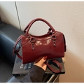 Dettaglio borsa a mano rosso scuro lucido con anelli e borchie in metallo nero - Borgogna
