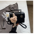 Close-up of black litchi grain handbag with star ornament and plush bear charm - Black