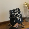 Black pebbled leather bucket bag featuring a pearl bow and silver heart pendant detail - Black