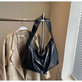 Detail of a black leather hobo bag with wide shoulder strap hanging on a metal rack - Black