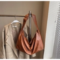 Detailed view of brown hobo bag with natural folds hanging on a metal rack - Brown