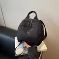 Elegante borsa a conchiglia in nylon nero con logo M metallico e manico superiore - Nero