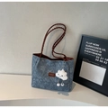 Détail d'un sac cabas en denim floral avec anses en cuir tressé et pendentif en nuage - Bleu et Café