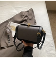 Contrast panel pillow bag with textured flap and gold shell clasp shown in lifestyle set - Black