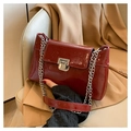 Close-up of vintage burgundy patent leather handbag with silver chain and metal buckle detail - Red