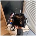 Détail du sac à dos en cuir noir brillant avec boucles verticales et pompon en perles - Blanc avec pendentif