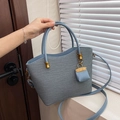 Detail van een blauwe geweven draagtas met een mini-hanger en goudkleurig metalen beslag - Blauw