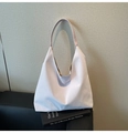 Détail du sac hobo blanc avec texture verticale posé sur un livre noir élégant - Violet