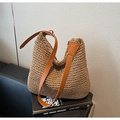 Detail of hand-woven straw hobo bag with brown leather strap on urban books - Brown