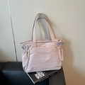 Sac fourre-tout minimaliste en nylon rose avec côtés froncés posé sur un livre - Violet