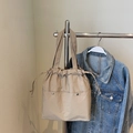 Minimalist beige nylon tote bag with drawstring closure and rivet details shown on hanger - Khaki