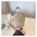 Detail of beige lychee leather mini bag featuring a smiley face charm and adjustable strap - Khaki