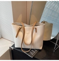 Detail view of white leather tote bag with brown handles and fashion trend logo text - Off White
