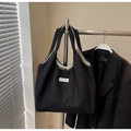 Détail macro du sac cabas noir minimaliste en maille texturée avec étiquette logo blanche - Noir