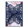 Close-up of laser-cut lace wedding invitation with navy blue ribbon and floral inner card - Magic Blue