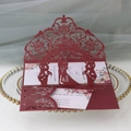 Macro detail of laser-cut burgundy wedding card with floral patterns and couple silhouette - Dark Red