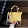 Close-up of bright yellow litchi pattern tote bag with a cute elephant charm on wooden stairs - Elephant Charm Style / Yellow