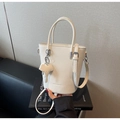 Gros plan du sac seau blanc à motif litchi avec breloque éléphant et bandoulière amovible - Blanc Cassé