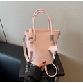 Gros plan du sac seau rose en cuir grainé avec breloque éléphant et bandoulière réglable - Rose