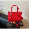 Close-up of red lychee pattern leather handbag with a cute elephant charm accessory - Elephant Charm Style / Red