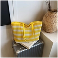 Detail of woven tote bag with yellow and white stripes and leather handle on a suitcase - Yellow