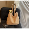 Bolso tote grande de paja tejida beige con correas de cuero sobre silla oscura - Caqui