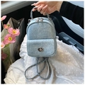 Détail du mini sac à dos en denim bleu clair avec fermoir rotatif et bandoulière chaîne - Bleu