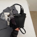 Close-up of black bucket bag with leather texture and houndstooth scarf detail - Black