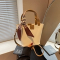 Cream bucket bag with brown handle and houndstooth scarf detail in hand - White & Khaki