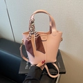 Pink luxury bucket bag with silk scarf handle and long strap displayed on sofa - Pink