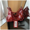 Detail of burgundy waxed leather hobo bag with woven strap and metallic charms - Red