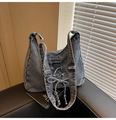 Détail du sac seau en denim bleu avec nœud lacé et bandoulière réglable en métal - Bleu clair