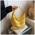Detail of yellow and white striped mesh tote with leather handles on a silver suitcase - Yellow