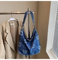 Dettaglio della borsa hobo in denim blu con patchwork di lettere vintage e ricami sfrangiati - Blu scuro