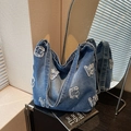 Borsa tote in denim blu slavato retrò con lettere sfrangiate in un ambiente moderno - Blu Denim