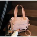 Detail der hellrosa Stofftasche mit Reißverschlusstasche und Tragegurt auf Holztreppe - Rosa