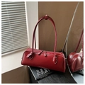 Detailed view of dark red leather baguette bag with dual zippers and smooth texture - Red