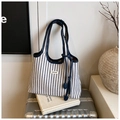 Close-up of blue and white striped canvas tote bag with leather trim on a metal suitcase - Blue