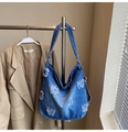 Dettaglio della borsa tote in denim blu con lettere a taglio vivo e design stile Hobo - Blu Denim