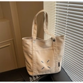 Detail of beige canvas tote with signature four-corner blue stitching on dark leather surface - Khaki