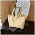 Detail of cream crocodile embossed tote bag with dual shoulder straps on a sleek table - Yellow
