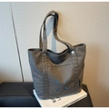 Detail of dark grey canvas tote bag featuring blue X-shaped stitching and side woven label - Dark Brown
