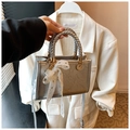 Details der silbernen Metallic-Handtasche mit gewebtem Griff und weißer Spitzenschleife - Silber