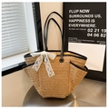 Beige straw tote bag with black handles and lace bow detail on a stylish round table - Khaki