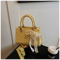 Detail einer gelben Handtasche mit geflochtenem Griff und Perlenherz-Anhänger - Gelb