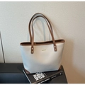 Detail of lychee pattern leather tote bag with brown trim on vintage book - Gray