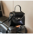 Close-up of a glossy black leather shoulder bag with silver chain and bow buckle detail - Black