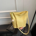 Chic yellow textured leather bucket bag with braided strap and spherical charm - Yellow