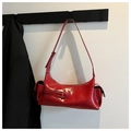 Detail view of red glossy crossbody dumpling bag with polished finish and side pocket - Red