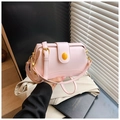 Pink leather handbag detail with golden hardware and yellow decorative buckle on a desk - Pink